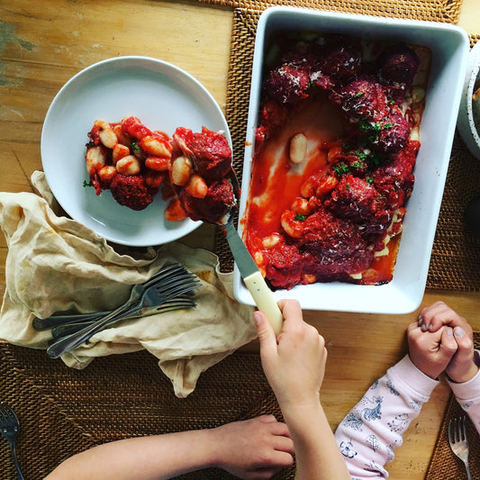 kids plating up baked gnocchi with meatballs