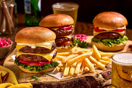 Three burgers with fries and a beer