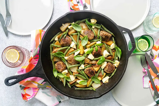 cast iron pan with beef rissoles and vegetables inside