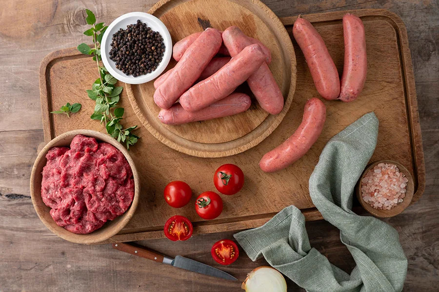 Chopping board with sausages on it and a bowl of beef mince