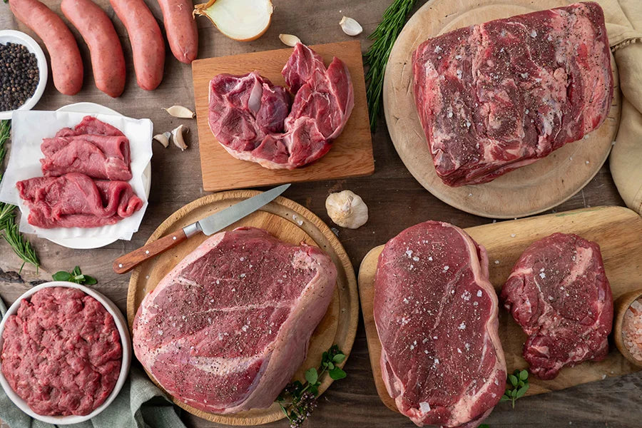 Wooden kitchen table filled with raw beef cuts