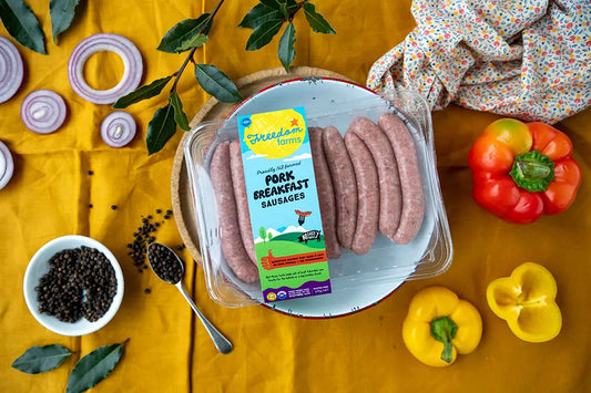 Packet of Pork breakfast sausages on top of plate on kitchen table with mustard table cloth