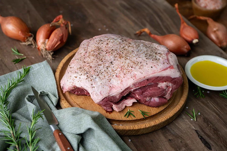 lamb roast on chopping board with shallots and oil