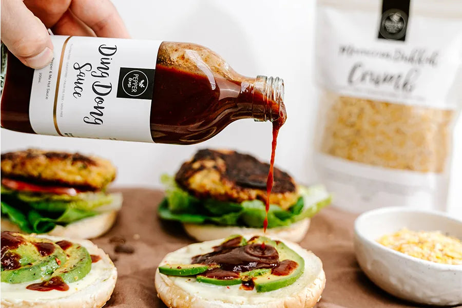 person pouring jarred sauce onto open burgers