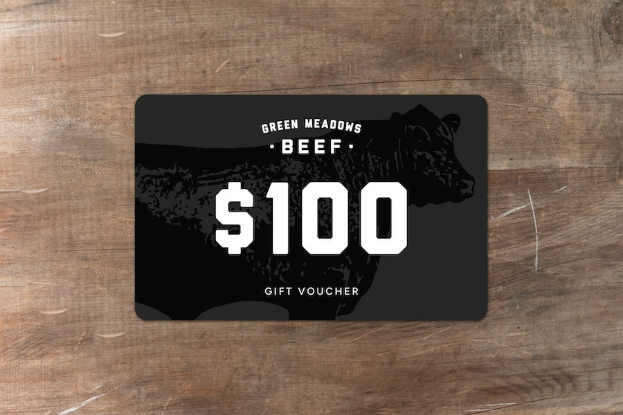 Green Meadows Beef gift voucher for $100 sitting on wood bench