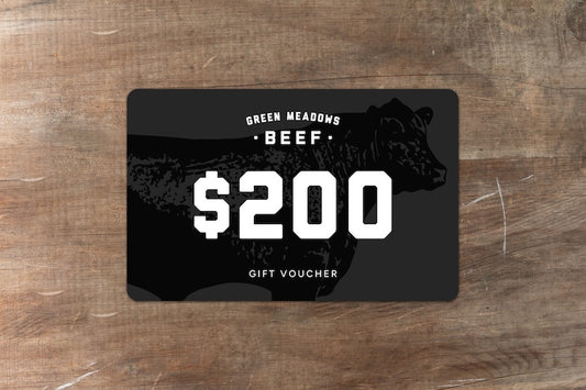 Green Meadows Beef gift voucher for $200 sitting on wood bench