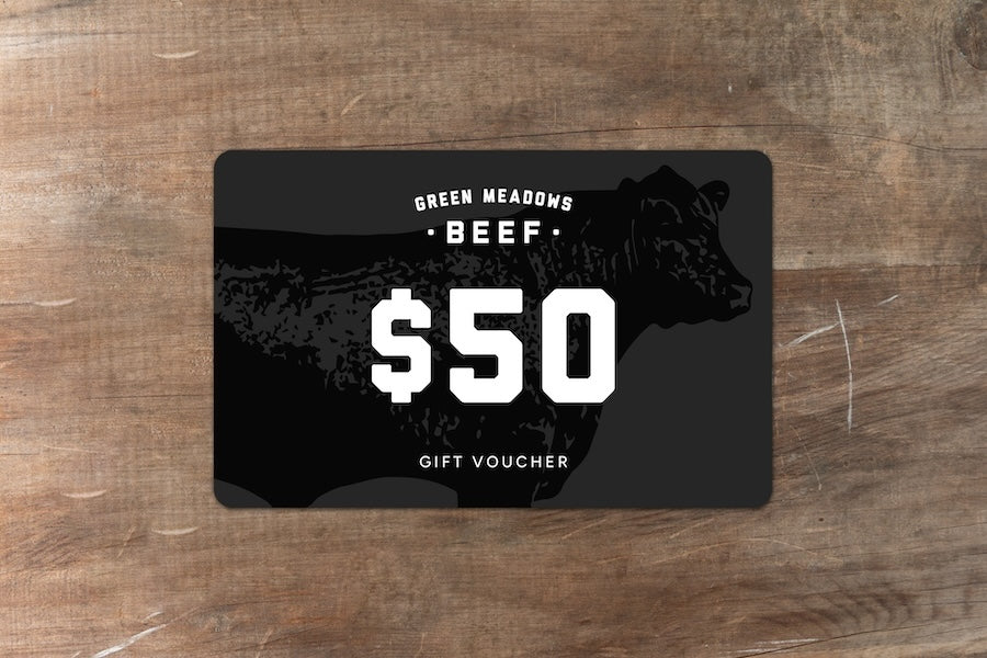 Green Meadows Beef gift voucher for $50 sitting on wood bench